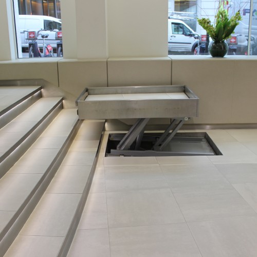 Wheelchair lift rises out of the floor and moves over the steps 
